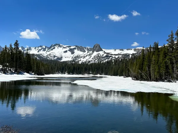 Scenic view of Lake Mary with snow along the shoreline and the Mammoth Crest mountains in the background