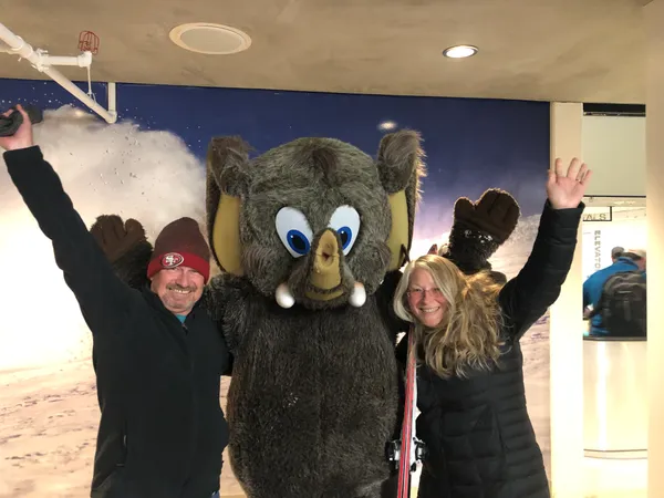 Michael and partner posing with Woolly the Mammoth Mountain mascot in winter