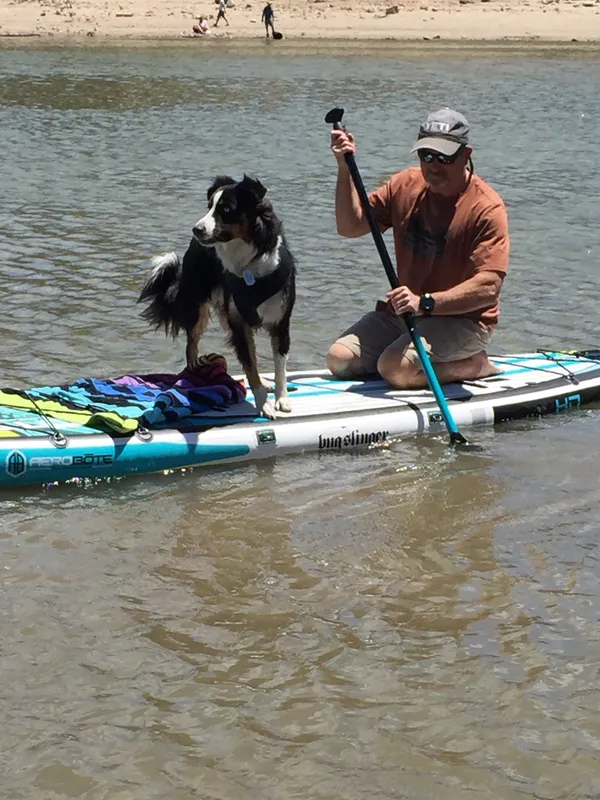 Michael paddleboarding with his dog on a clear alpine lake in Mammoth