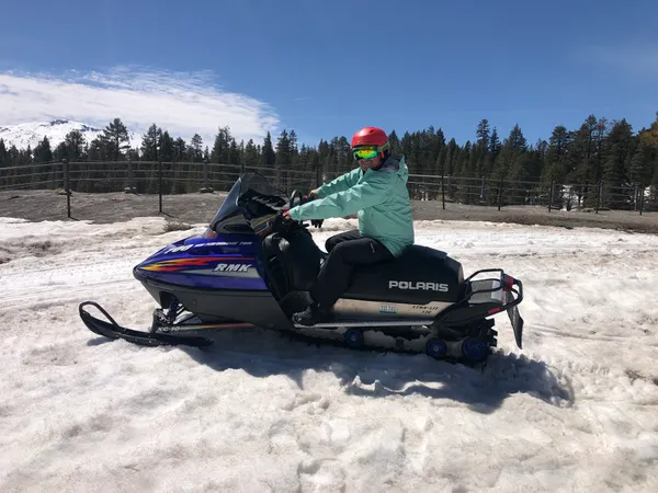Michael on a snowmobile surrounded by deep winter snow in Mammoth Lakes